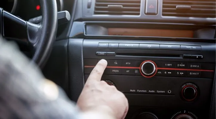 man changing the channel of the car radio