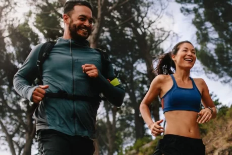man and woman running in the forest